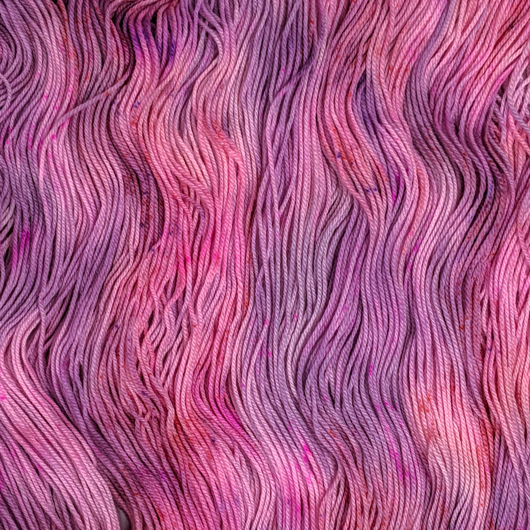 hand-dyed yarn in a variegated colorway of pink, peach and purple shades