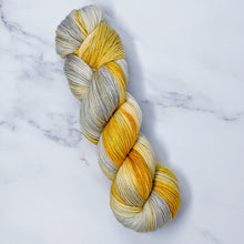 Load image into Gallery viewer, hand-dyed yarn in a variegated colorway of  golden yellows melingt into swirls of silver gray
