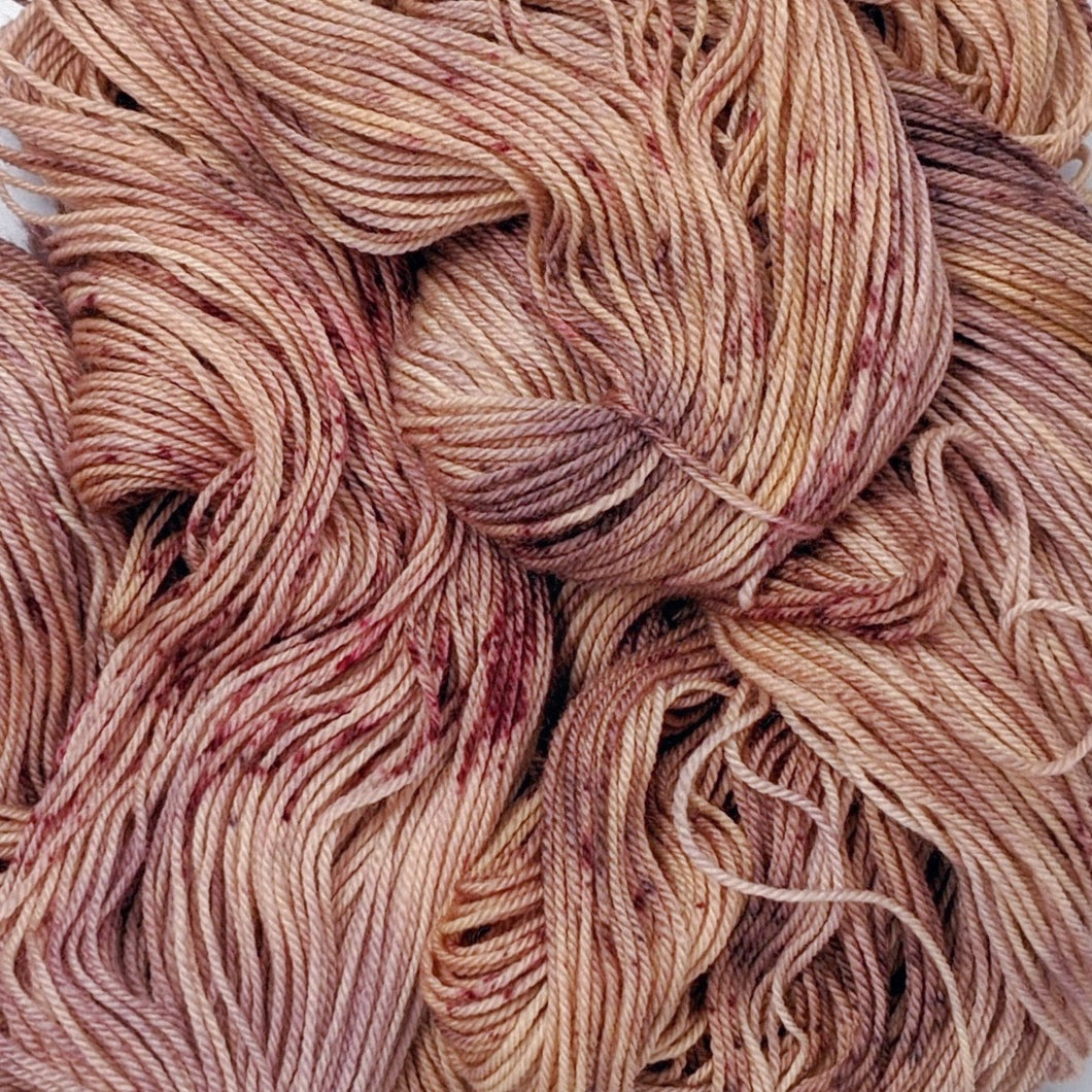 hand-dyed yarn in a variegated tonal colorway of rosey tonal browns with flashes of dark rose and chestnut brown