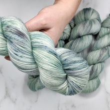 Load image into Gallery viewer, hand-dyed yarn in a variegated tonal colorway of icy blue, sea green and gray melting together like sunlight through water
