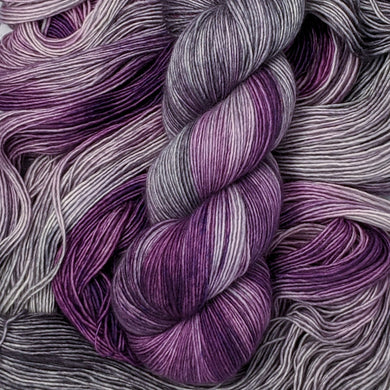 hand-dyed yarn in a variegated colorway of bursts of purple among waves of smokey gray